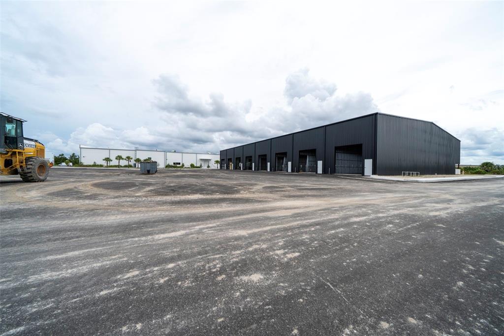 A large, dark-sided industrial warehouse building under construction on a dirt lot — 8411-8419 DUFFIE DRIVE, PUNTA GORDA, FL