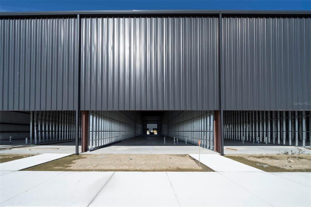 An exterior view of a modern, black metal-sided commercial building under construction on a sandy lot — 8411-8419 DUFFIE DRIVE, PUNTA GORDA, FL