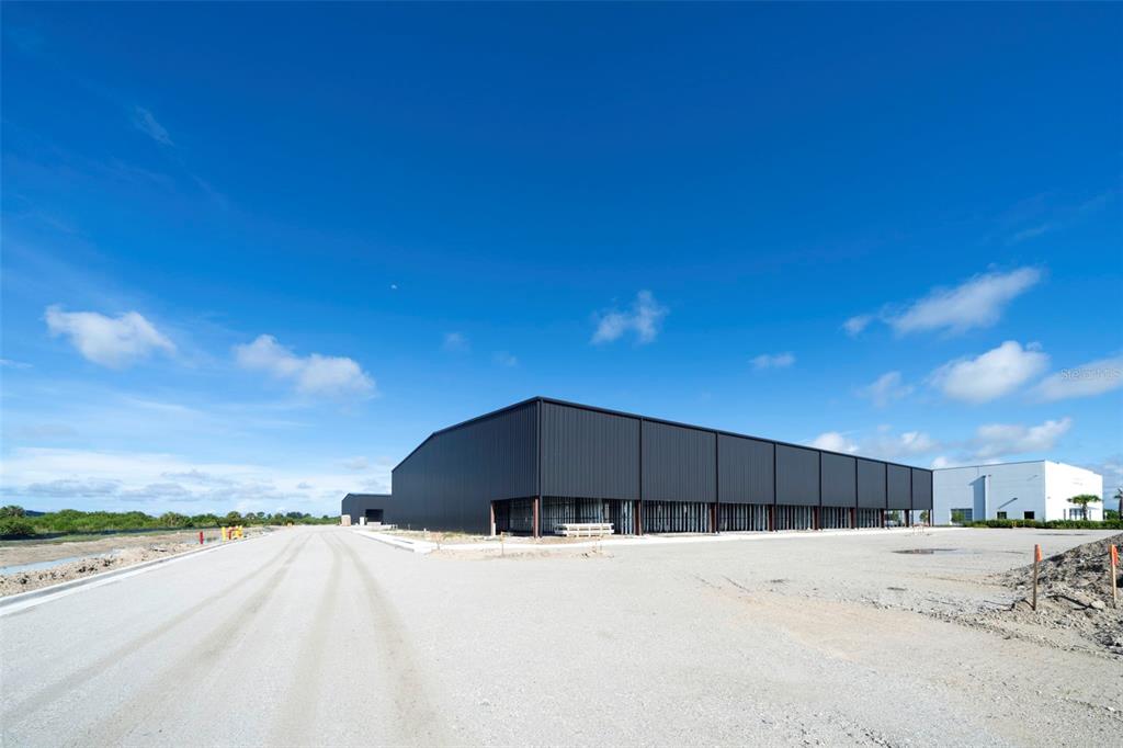 An unfinished warehouse interior features exposed metal framing, a concrete floor, and high ceilings — 8411-8419 DUFFIE DRIVE, PUNTA GORDA, FL