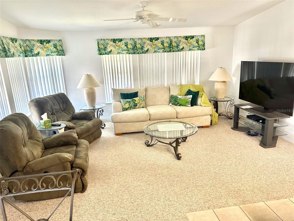 A living room features a beige sofa, two brown recliners, and a glass coffee table — 11244 101ST WAY UNIT 136, LARGO, FL