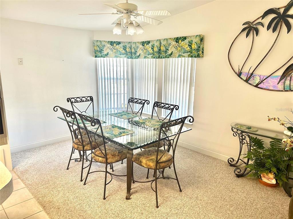 A dining room features a glass-topped table with six metal chairs and a ceiling fan — 11244 101ST WAY UNIT 136, LARGO, FL