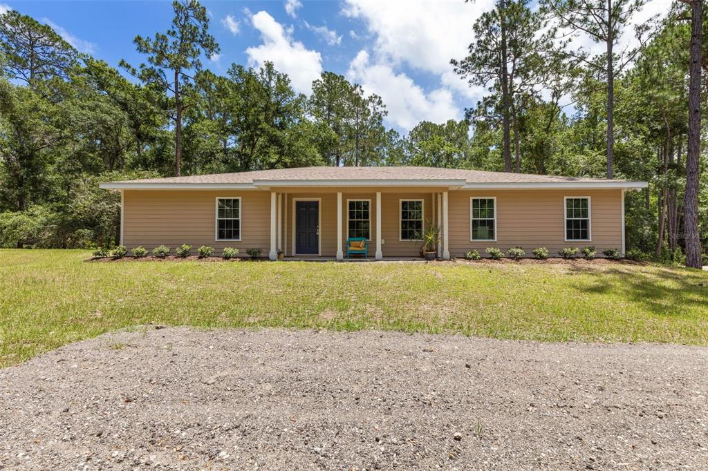 A spacious open-concept living room features wood-look flooring, a red sofa, and a vaulted ceiling — 3296 N OLD DIXIE HIGHWAY, BUNNELL, FL