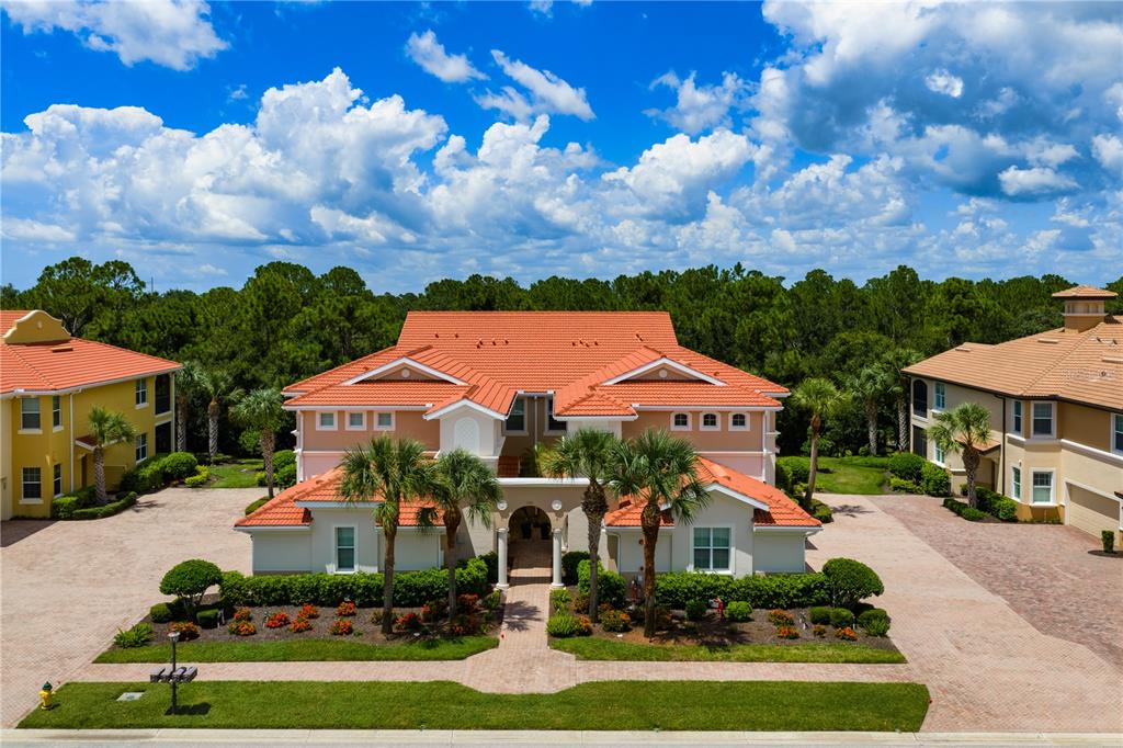 An exterior view of a multi-story residential building with a red tile roof and landscaping — 166 BELLA VISTA TERRACE UNIT 19A, NOKOMIS, FL