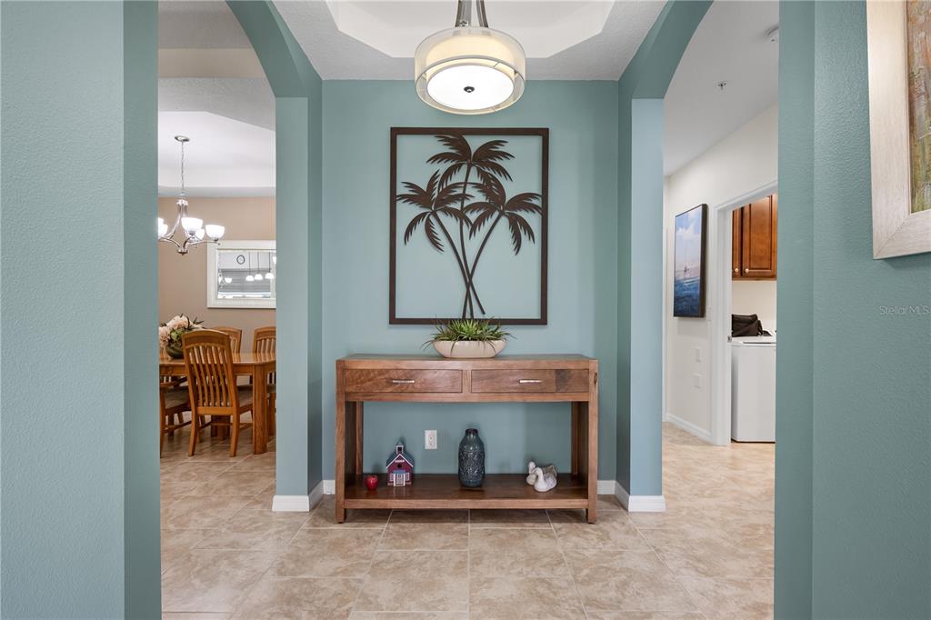 A foyer features a wooden console table, teal walls, and tile flooring — 166 BELLA VISTA TERRACE UNIT 19A, NOKOMIS, FL