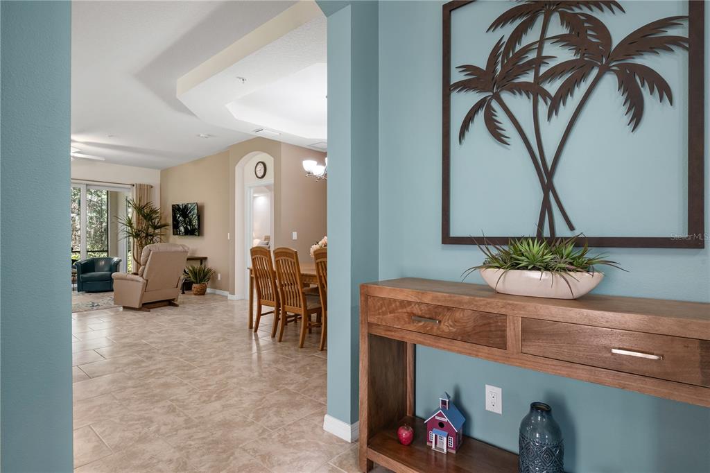 A wooden console table sits in a blue entryway with a palm tree wall decoration — 166 BELLA VISTA TERRACE UNIT 19A, NOKOMIS, FL