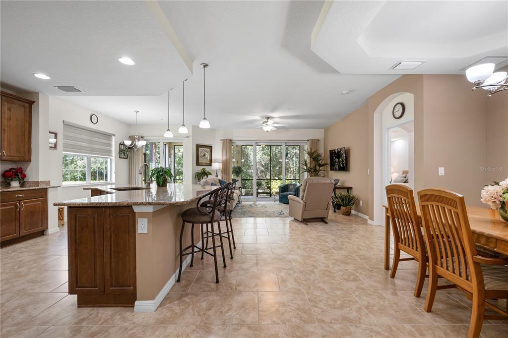 An open-concept kitchen and living area with tile flooring, granite countertops, and sliding glass doors — 166 BELLA VISTA TERRACE UNIT 19A, NOKOMIS, FL