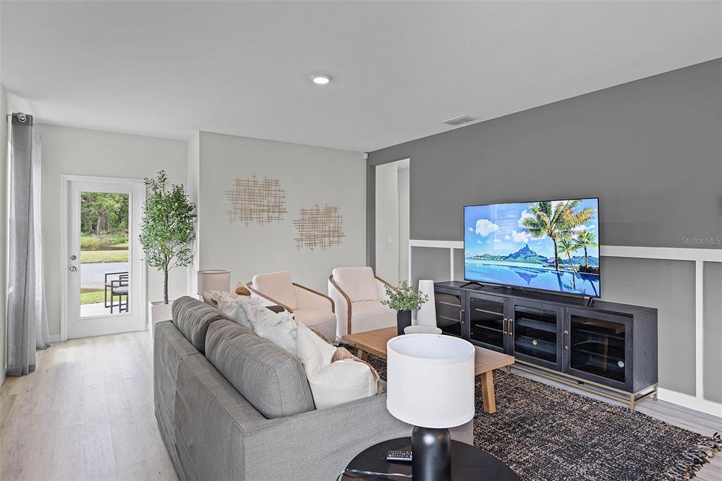 A living room features a gray sofa, two cream chairs, and a television on a console — 1514 LAS PALMAS STREET, LAKELAND, FL