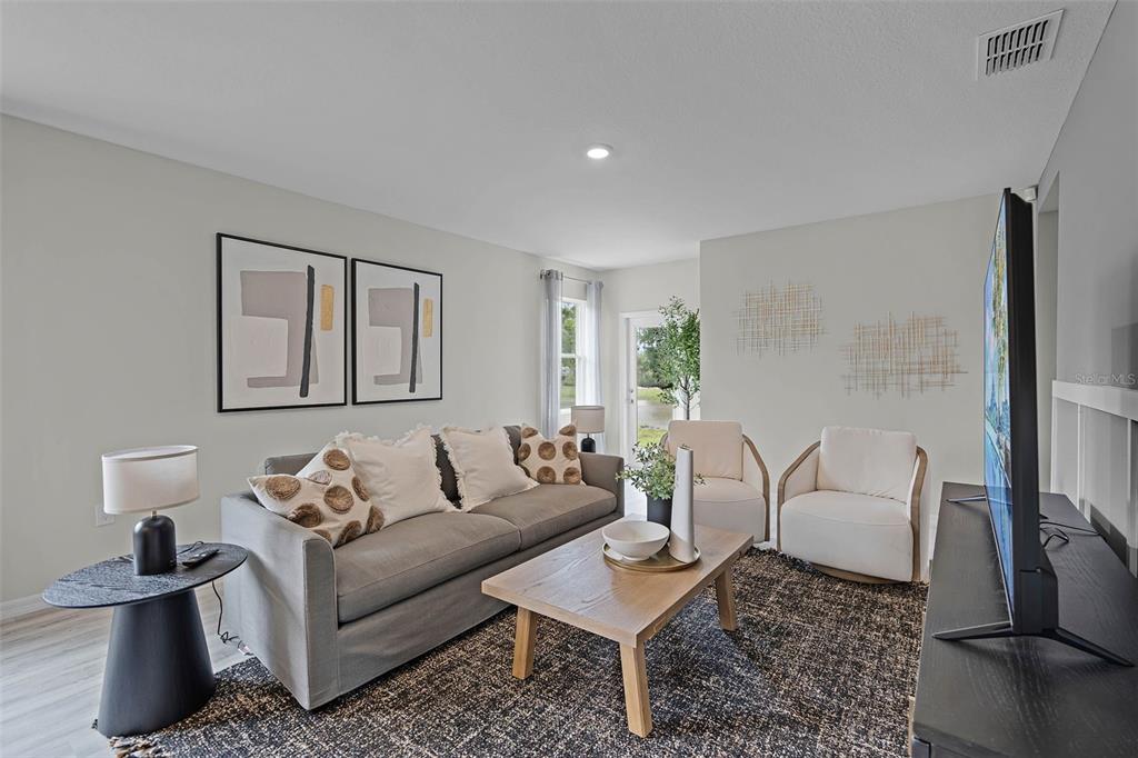 A living room features a gray sofa, two white chairs, a coffee table, and wall art — 1514 LAS PALMAS STREET, LAKELAND, FL