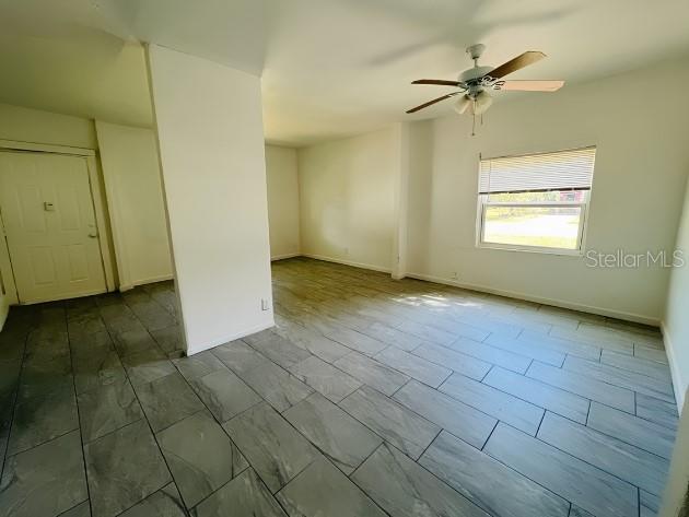 An empty room features gray tile flooring, a ceiling fan, and a window with blinds — 918 E 10TH STREET Unit B, SANFORD, FL
