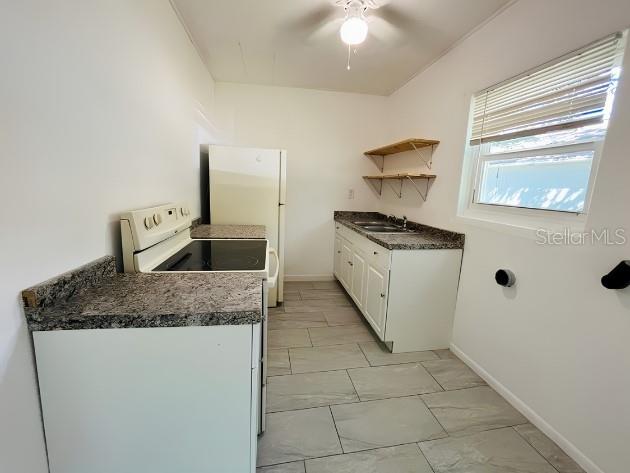 A kitchen features white cabinets, a refrigerator, a stove, and open shelving on the wall — 918 E 10TH STREET Unit B, SANFORD, FL