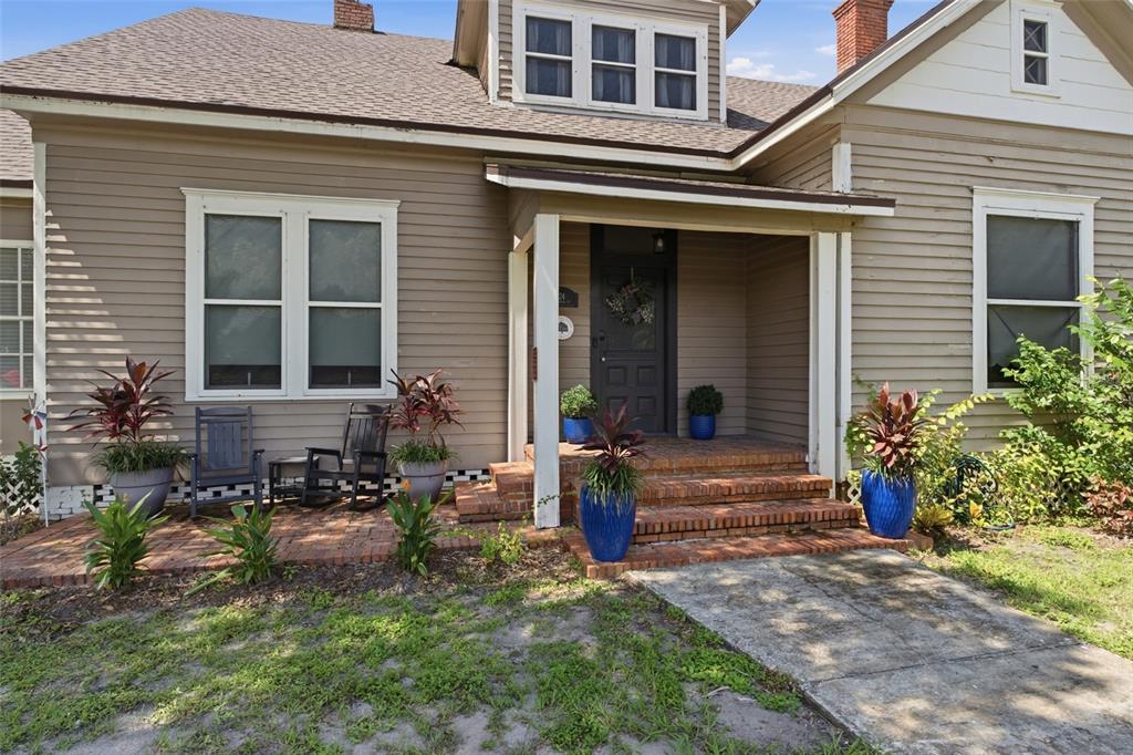A tan house features a brick porch, a dark front door, and several potted plants — 524 E MAGNOLIA STREET, ARCADIA, FL