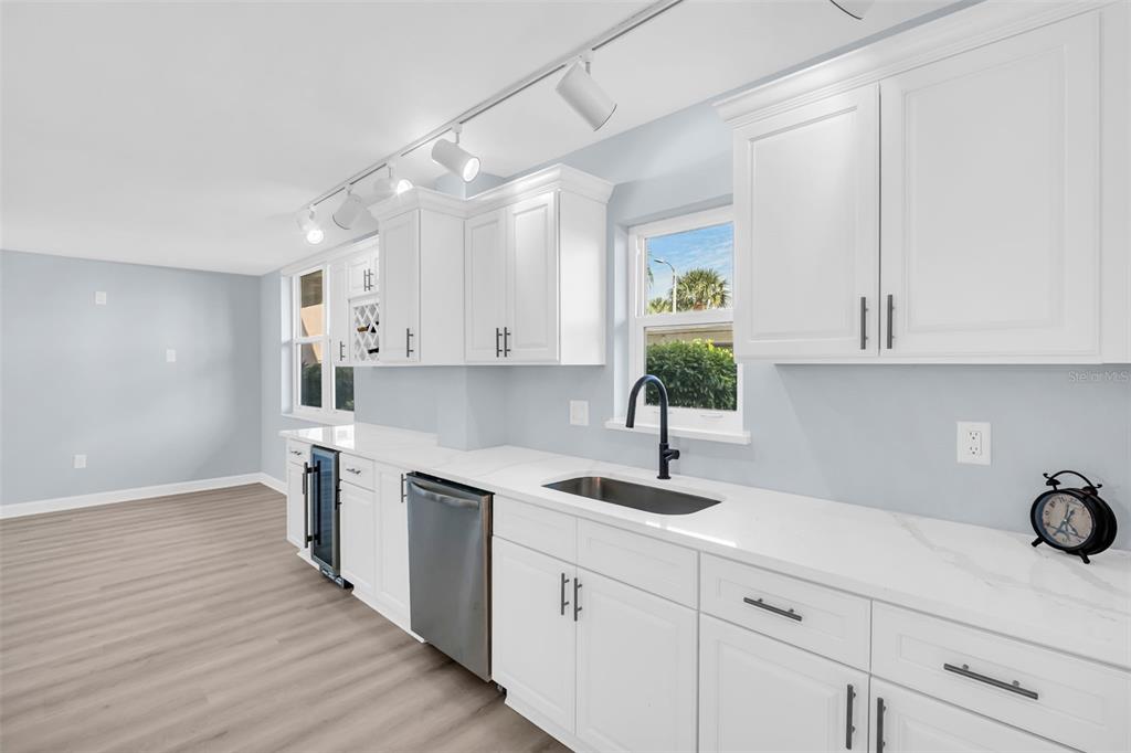 A kitchen features white cabinets, stainless steel appliances, a sink, and light-colored flooring — 7930 SUN ISLAND DRIVE S UNIT 104, SOUTH PASADENA, FL
