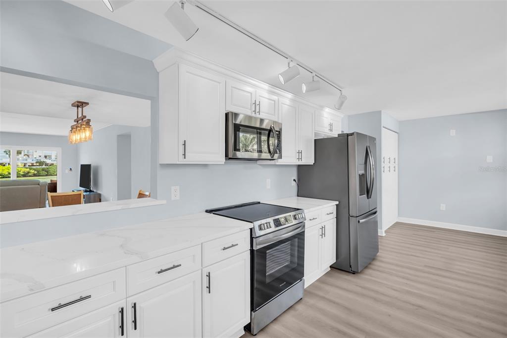 A kitchen features white cabinets, stainless steel appliances, and light-colored countertops — 7930 SUN ISLAND DRIVE S UNIT 104, SOUTH PASADENA, FL