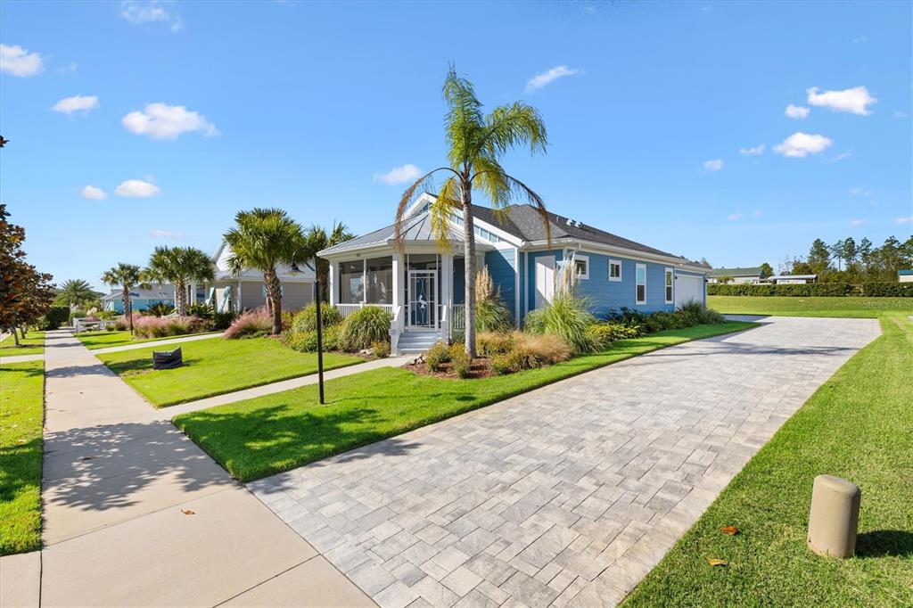 A blue single-story house features a paved driveway, a front porch, and palm trees — 1052 SUGAR LOAF KEY LOOP, LADY LAKE, FL