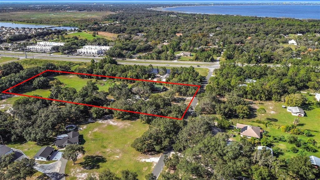 An aerial view shows a rectangular property outlined in red amidst a wooded residential area — 4980 DISSTON DRIVE, ST CLOUD, FL