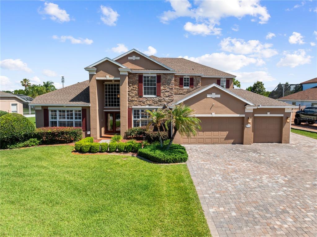 A two-story house with a stone facade, brown stucco, and a paved driveway — 1620 MARINA LAKE DR, KISSIMMEE, FL