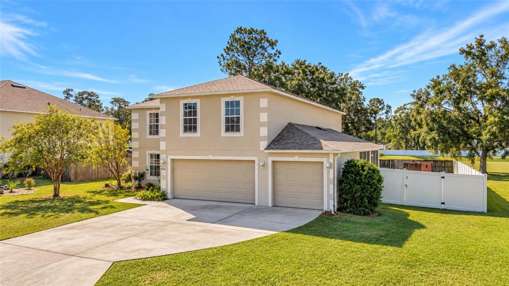 A two-story house with a three-car garage and a white vinyl fence in the yard — 4540 SE 30TH STREET, OCALA, FL