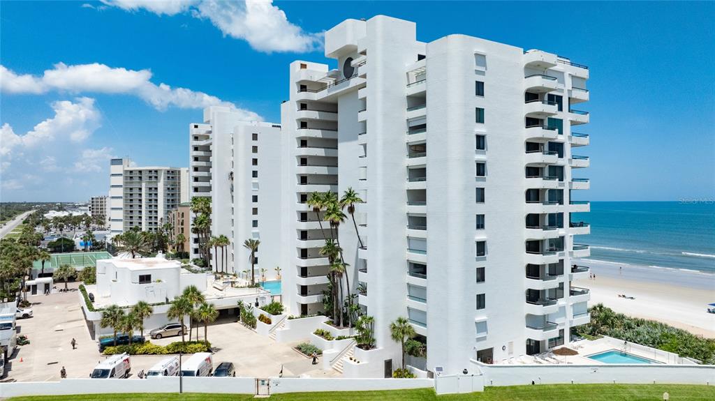An aerial view of a white high-rise condominium building located directly on a sandy beach — 5275 S ATLANTIC AVENUE UNIT 1007, NEW SMYRNA BEACH, FL
