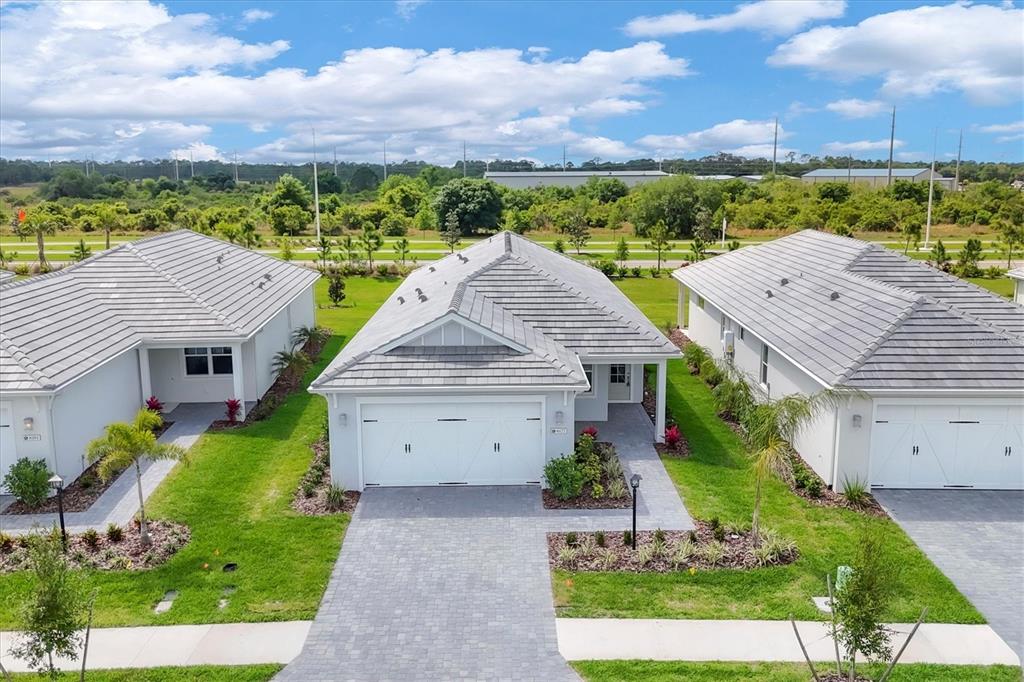 An aerial view shows three suburban houses with gray tiled roofs and paved driveways — 8177 STERNWAY ROAD, SARASOTA, FL