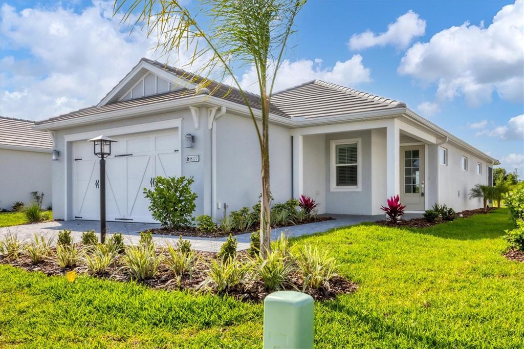 A single-story house with a white garage, gray exterior, and a palm tree in front — 8177 STERNWAY ROAD, SARASOTA, FL