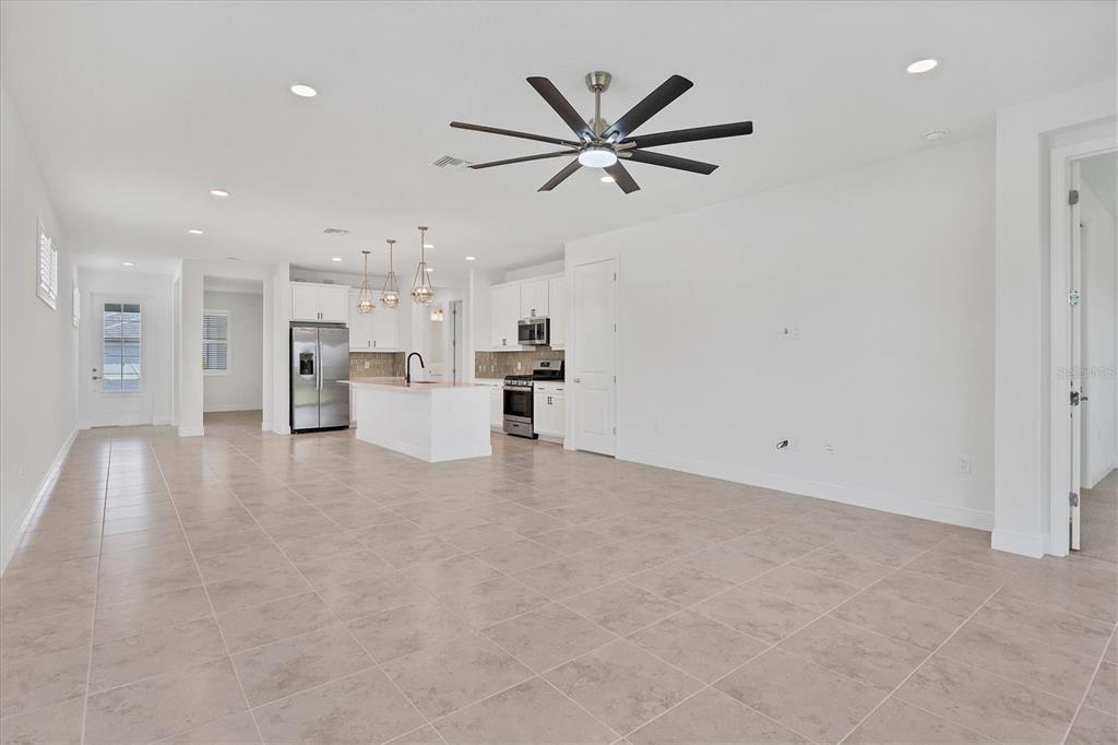 A spacious, open-concept kitchen and living area with white cabinetry, stainless appliances, and tile flooring — 8177 STERNWAY ROAD, SARASOTA, FL