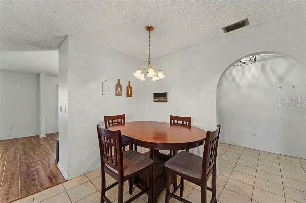 A living room features a stone fireplace, tile flooring, a ceiling fan, and a leather sofa — 11022 SALT TREE DRIVE, PORT RICHEY, FL