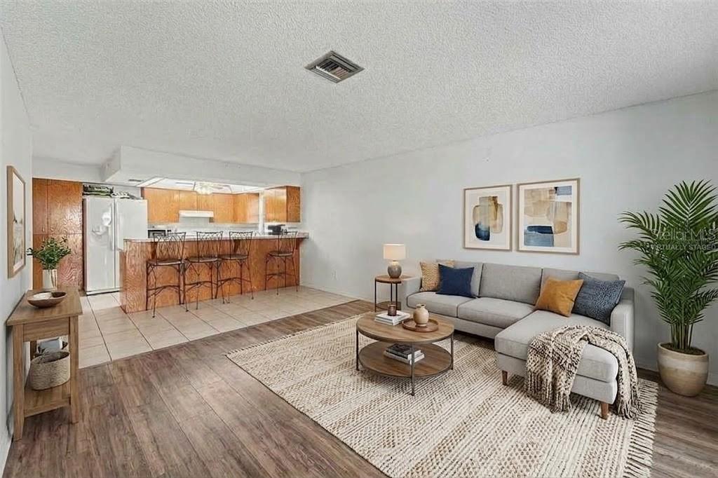 A kitchen features wood cabinets, white appliances, granite-look countertops, and a tray ceiling with lighting — 11022 SALT TREE DRIVE, PORT RICHEY, FL