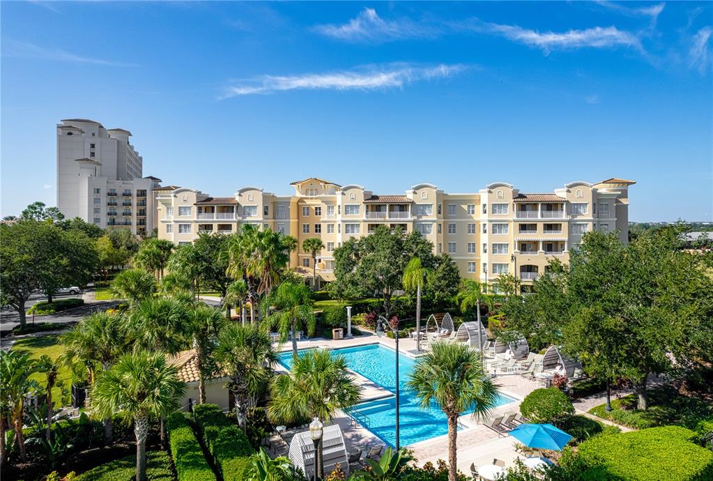 A multi-story hotel building overlooks a swimming pool surrounded by palm trees and lounge chairs — 8495 MIRACLE DRIVE UNIT 206, CHAMPIONS GATE, FL