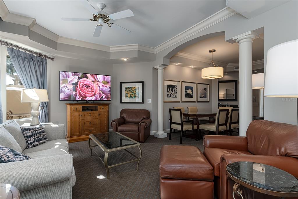 A living room with a gray sofa, brown leather chairs, and an adjacent dining area — 8495 MIRACLE DRIVE UNIT 206, CHAMPIONS GATE, FL