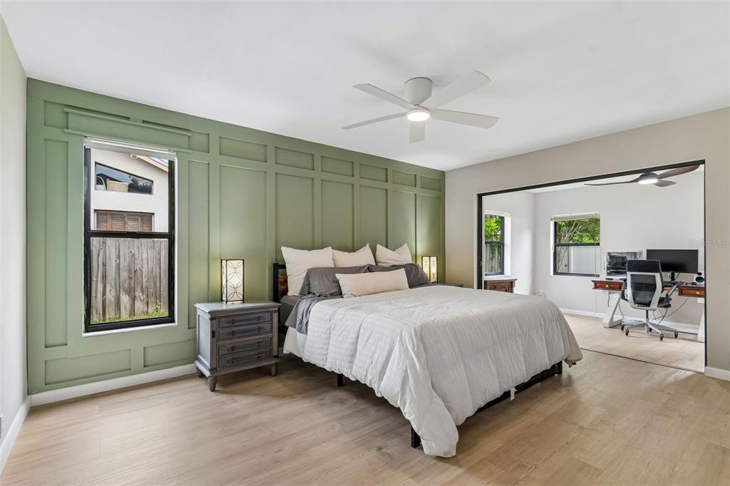 A bedroom features a sage green paneled accent wall, light wood floors, and an adjoining office — 525 WALKER ROAD, SAFETY HARBOR, FL