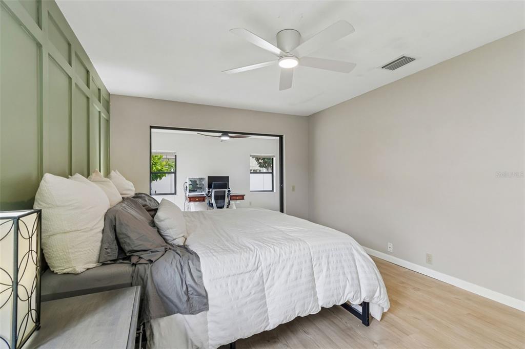 A bedroom features a green paneled accent wall, a white ceiling fan, and an office nook — 525 WALKER ROAD, SAFETY HARBOR, FL