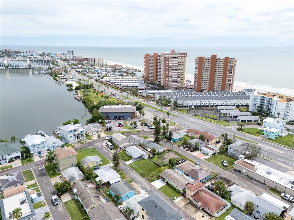 An aerial view shows a coastal neighborhood with houses, a road, and high-rise buildings — 2ND STREET E, REDINGTON SHORES, FL