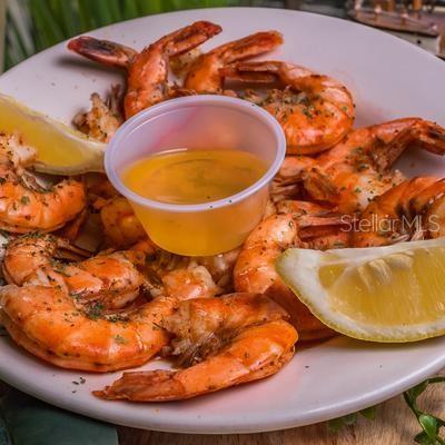 A plate of cooked shrimp with a small container of dipping sauce and lemon wedges — 18421 US-41, LUTZ, FL