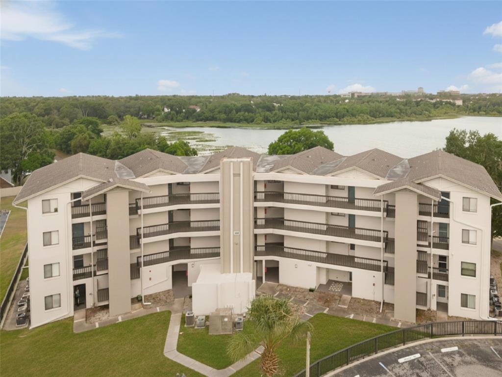 A covered balcony features tiled flooring, patio furniture, and a view of a lake — 1068 LOTUS PARKWAY UNIT 834, ALTAMONTE SPRINGS, FL