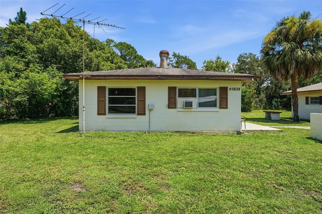 A single-story, light-colored concrete block house with brown shutters and a metal roof — 45828 DEER STREET, PAISLEY, FL