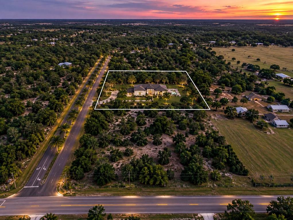 An aerial view shows a wooded plot of land adjacent to a paved road — 41155 STATE RD 64 EAST, MYAKKA CITY, FL