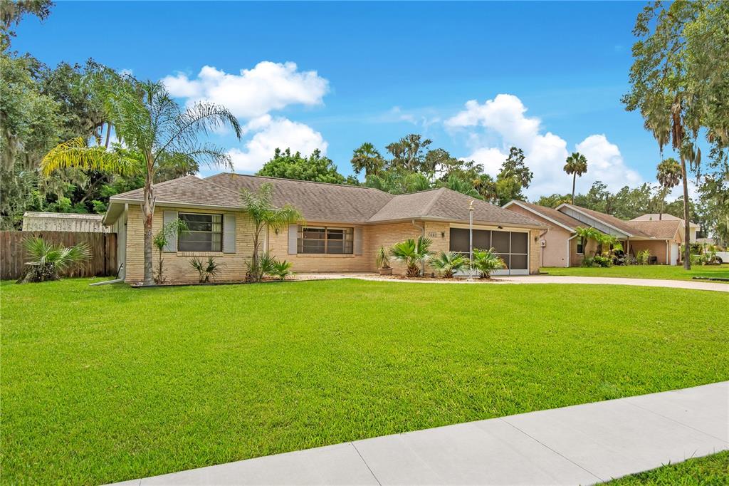A single-story brick house with a lawn, palm trees, and a screened-in garage — 605 BOARS HEAD DRIVE, PORT ORANGE, FL