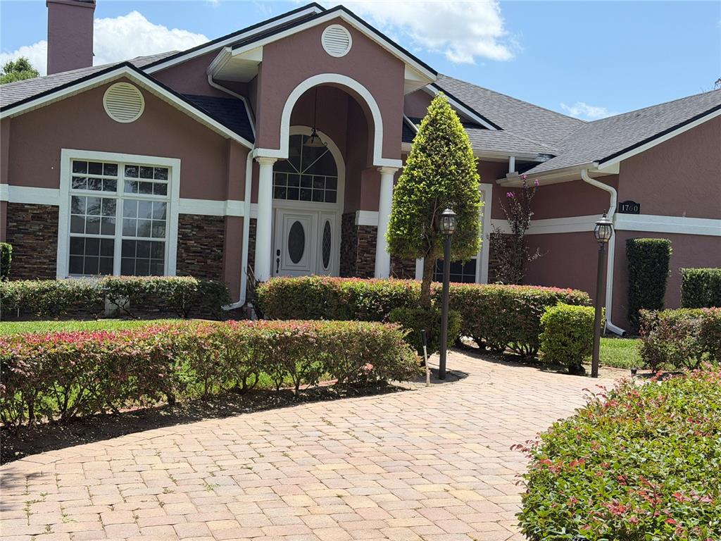 A single-story house with a paved driveway, stone accents, and a covered arched entryway — 1760 LAKE TERRACE DR, EUSTIS, FL