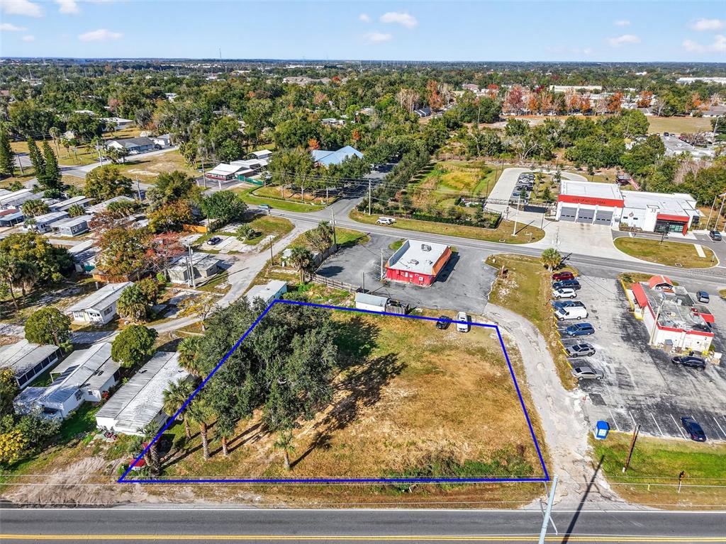 An aerial view shows a vacant, rectangular lot outlined in blue next to a paved road — OLD US-441 W, MOUNT DORA, FL
