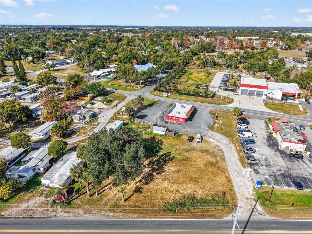 An aerial view shows a vacant lot, a small red building, and nearby commercial structures — OLD US-441 W, MOUNT DORA, FL