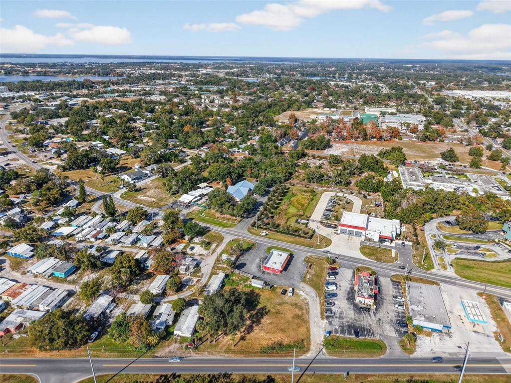 An aerial view shows a commercial area with buildings, parking lots, and surrounding residential neighborhoods — OLD US-441 W, MOUNT DORA, FL