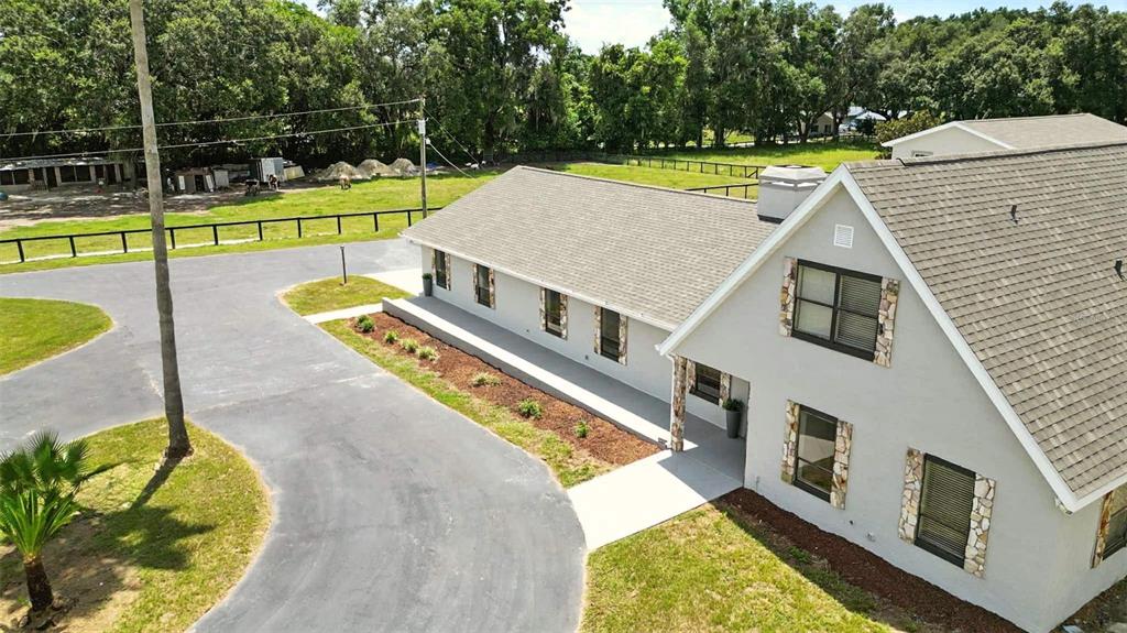An aerial view shows a gray house with stone accents and a paved driveway — 1960 SE 150TH STREET, SUMMERFIELD, FL