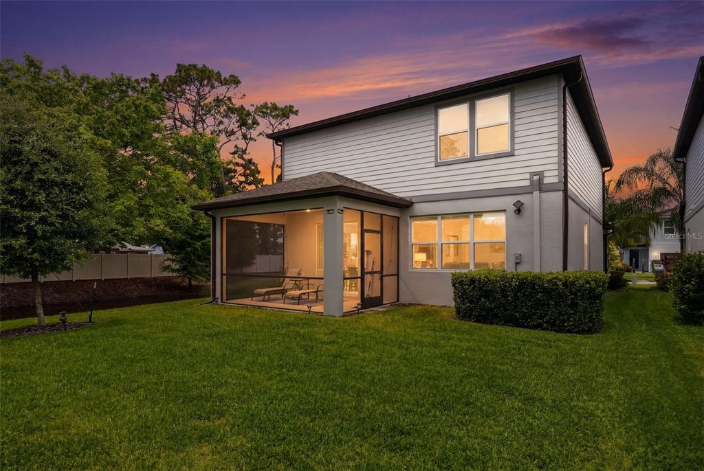 The exterior of a two-story house features a screened-in patio and a grassy backyard — 2949 PIER POINTE LANE, CLEARWATER, FL