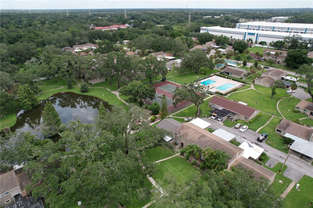 An aerial view shows a residential complex with a pond, tennis courts, and a pool — 7907 SABAL DRIVE, TEMPLE TERRACE, FL
