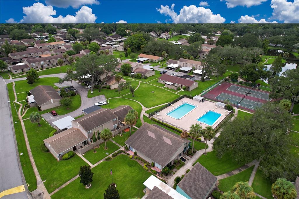 An aerial view shows a residential complex with swimming pools, tennis courts, and landscaped grounds — 7907 SABAL DRIVE, TEMPLE TERRACE, FL