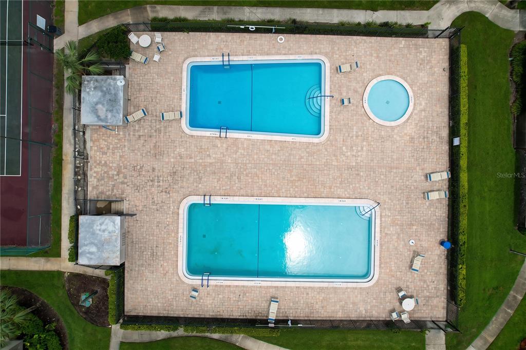 An aerial view shows two rectangular swimming pools and a circular spa on a paved deck — 7907 SABAL DRIVE, TEMPLE TERRACE, FL