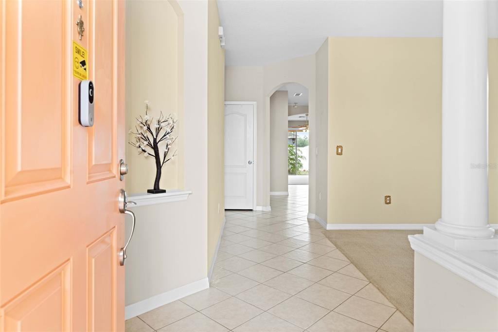 An entryway with a peach-colored door, tile flooring, and a view into the home's interior — 699 WINTHROP DRIVE, SPRING HILL, FL