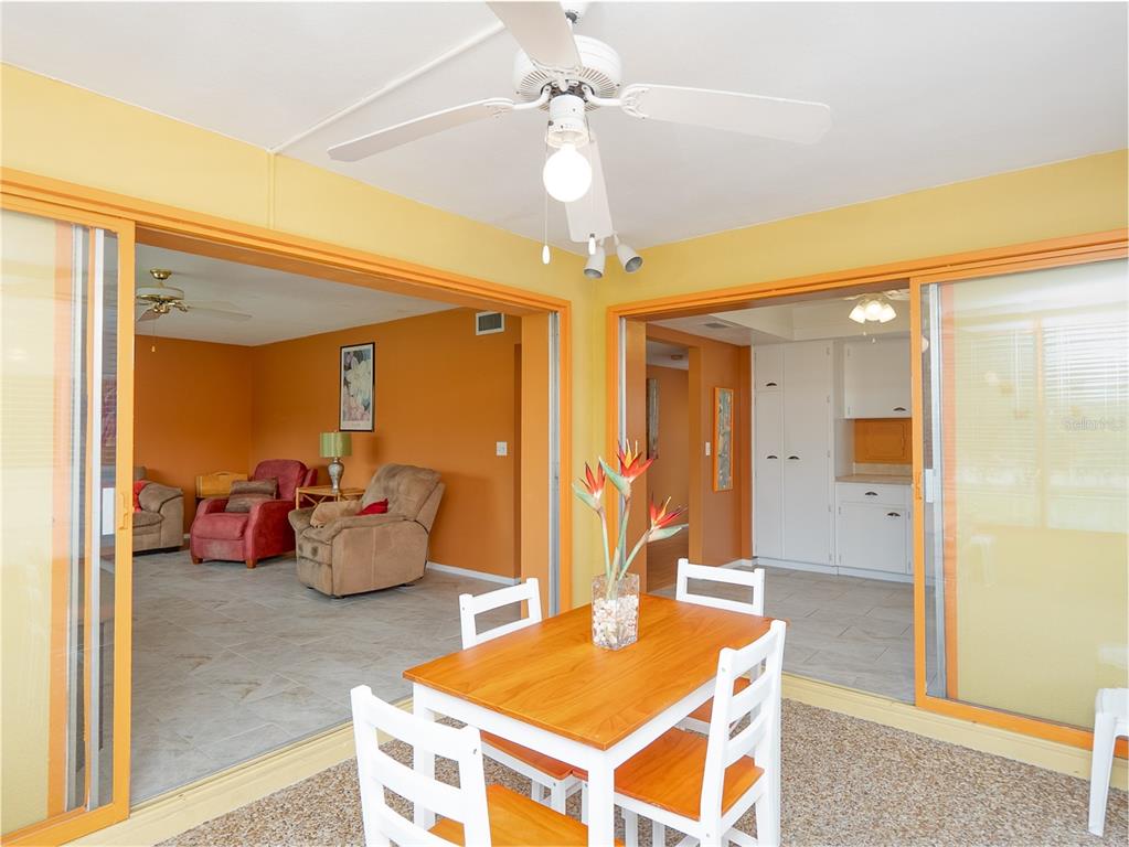 A hallway with orange walls, wood-look flooring, and a three-panel birch tree wall art piece — 3816 ROXANE BLVD UNIT 158, SARASOTA, FL