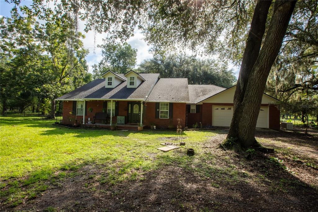 A single-story brick house with a front porch, dormer windows, and an attached two-car garage — 9284 NW COUNTY ROAD 225, STARKE, FL