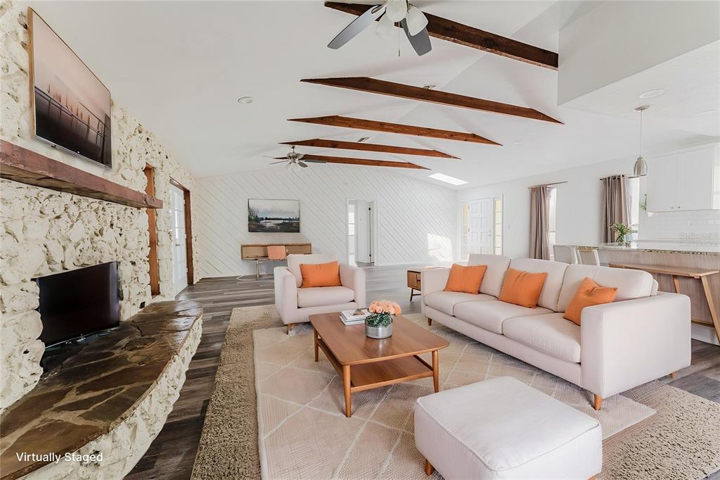 A living room features a stone fireplace, exposed ceiling beams, and light-colored furniture — 96 E BAYSHORE DRIVE, PORT ORANGE, FL